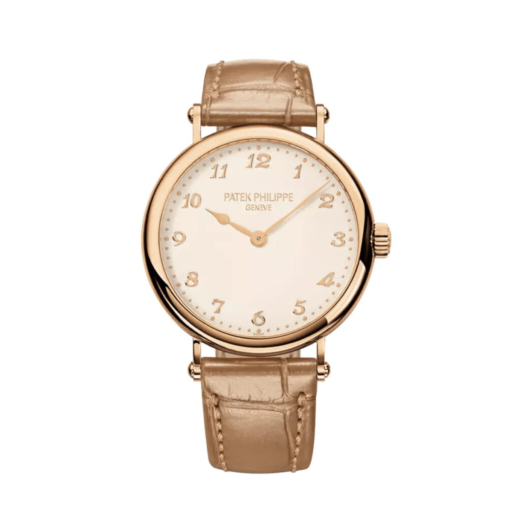 Eine goldene Patek Philippe Calatrava Armbanduhr mit beigem Lederarmband, goldenen arabischen Ziffern und goldenen Stunden- und Minutenzeigern auf einem weißen Zifferblatt. Das Logo der Marke ist in der Nähe der 12-Uhr-Position aufgedruckt.