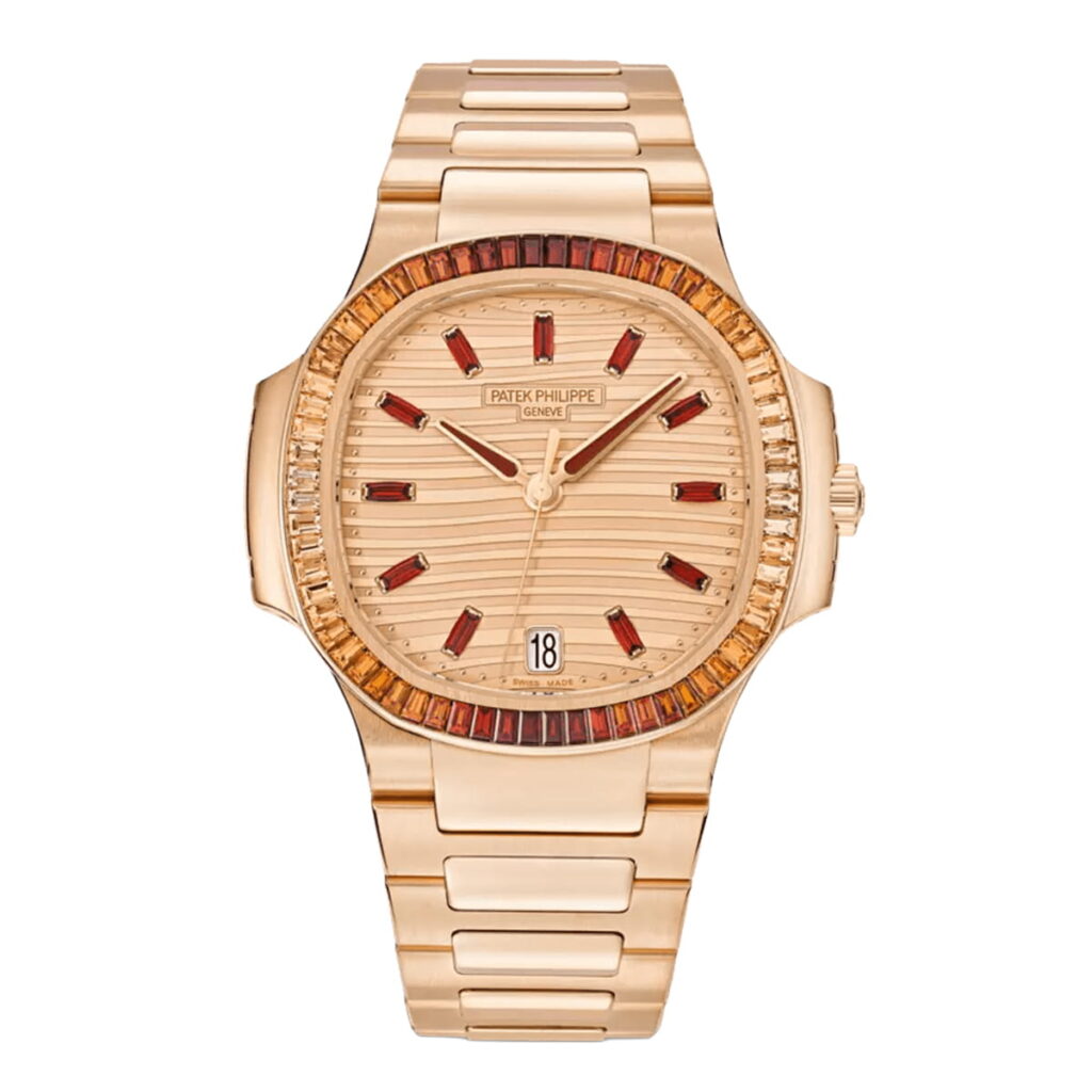 Eine goldene Patek Philippe Nautilus Armbanduhr mit passendem Goldarmband, roten und klaren Edelsteinen auf der Lünette, goldenem Zifferblatt, roten Stundenmarkierungen und einem Datumsfenster bei 6 Uhr.